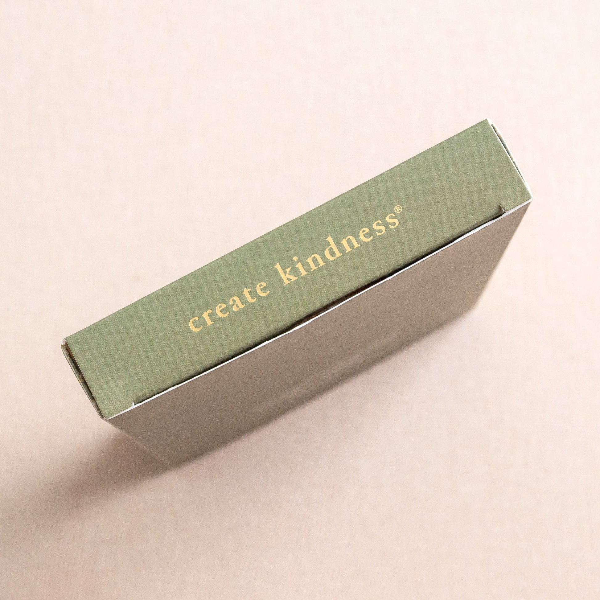 Rectangular box with 'create kindness' text on a beige background